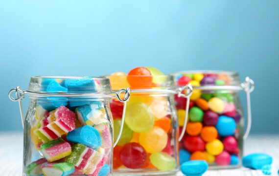 Colorful,Candies,In,Jars,On,Table,On,Blue,Background,Background
